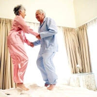 ágyon ugráló idős pár, boldogság